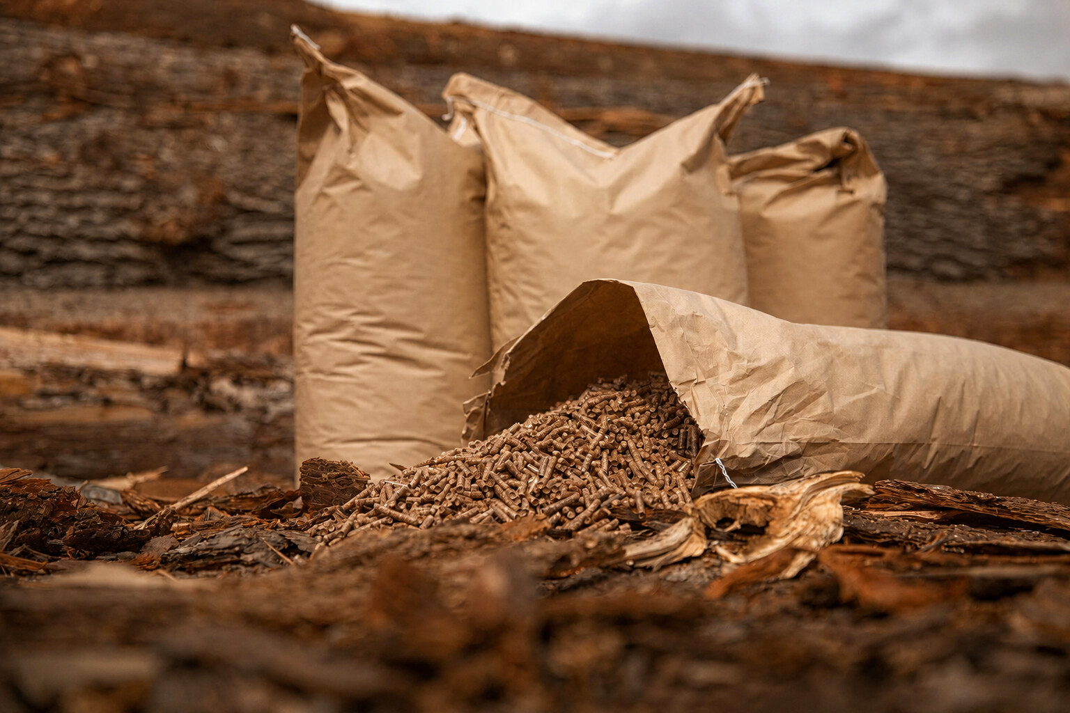 Holzpellets in einem geöffneten Papiersack vor weiteren Säcken im Sägewerk.